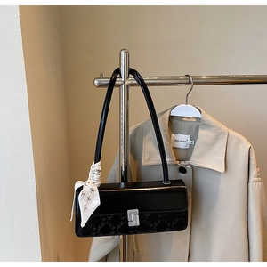Detail of black leather handbag with silver S-buckle and decorative floral silk scarf