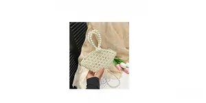 Detail of white handmade pearl beaded crossbody bag with round handle and floral background