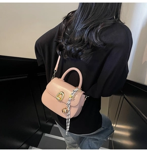 Pink small square bag with golden horseshoe buckle and decorative silk scarf detail