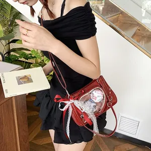 Detail of red patent leather Ita-bag with lace bow and badge display worn as crossbody