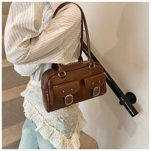 Detail of a large brown leather pillow bag featuring front pockets and silver buckle accents