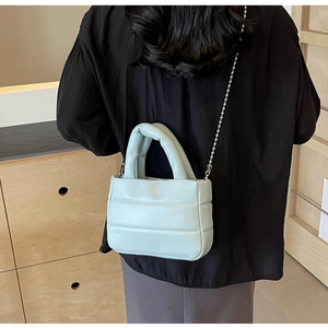 Back view of model wearing a light blue quilted crossbody bag with silver bead chain