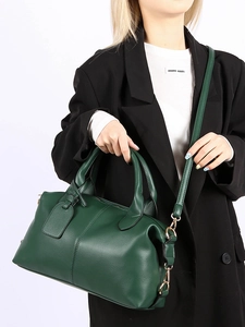 Detail of dark green pebbled leather Boston bag showing adjustable strap and metal hardware
