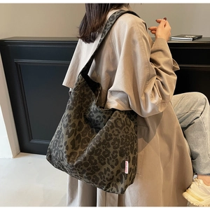Detail of grey leopard print tote bag with wide strap and minimalist woven side label