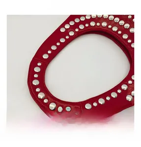 Vue détaillée de la poignée du sac en cuir rouge avec des rivets métalliques argentés