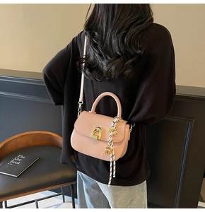 Detail of pink leather handbag with gold clasp, scarf accessory, and thin shoulder strap