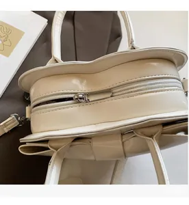 Close-up of smooth silver metal zipper and handles on cream white faux leather bag