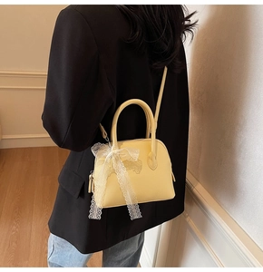 Détail d'un sac à main jaune pâle orné d'un nœud en dentelle blanche et bandoulière