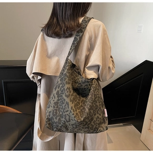 Detail of leopard print canvas tote bag with red brand label on olive green fabric