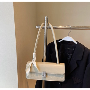 Detail view of cream rectangle bag with geometric embossing and silk scarf on a hanger