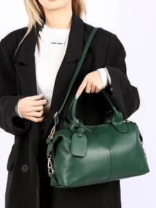 Detail of dark green pebbled leather bag with golden chain strap and refined texture