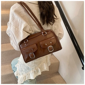Detail of dark brown leather shoulder bag featuring vintage silver buckle pockets