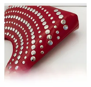 Détail d'un sac en cuir rouge vif orné de rivets métalliques argentés disposés en arc de cercle