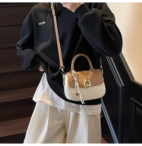 Detail of cream crossbody bag with brown flap and silk scarf on wooden stairs