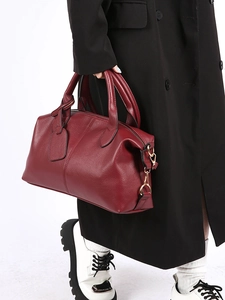 Classic burgundy Boston bag in textured lychee leather being held by a model