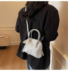 Vue détaillée du mini sac en cuir argenté avec nœud en dentelle porté par le mannequin
