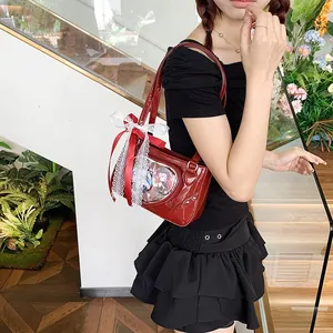 Detail of red patent leather ita bag featuring a heart-shaped window and lace bow