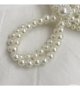 Detail of white faux pearl handbag strap featuring double-row large pearls and small accents