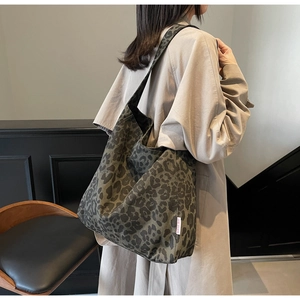 Detail of leopard print tote bag in olive and black canvas shown on shoulder