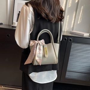 Sac seau minimaliste en cuir gris avec foulard décoratif et fermoir doré chic