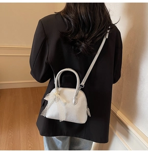 Gros plan d'un mini sac coquillage argenté avec un nœud en dentelle sur blazer noir