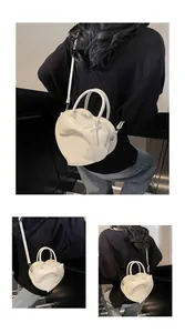Detail view of heart-shaped crossbody bag with bow accent and detachable shoulder strap