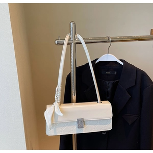 Detail of cream glossy leather handbag with geometric embossing and silk scarf accent