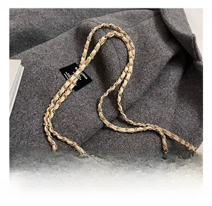 Close-up of golden interwoven chain strap on a beige quilted leather shoulder bag