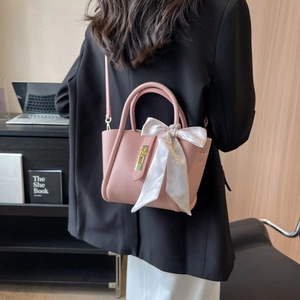Sac seau rose en cuir grainé avec foulard en soie et fermoir doré dans un décor de bureau
