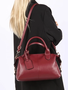 Close-up of wine red lychee grain Boston bag worn as a shoulder bag on black blazer