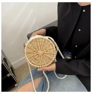 Detail of round woven straw bag with elegant pearl strap and secure drawstring closure