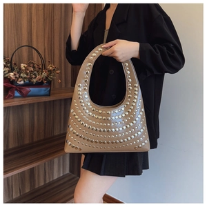 Détail du sac croissant kaki avec rivets argentés radiaux et finition brillante