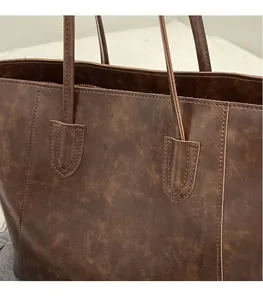Detailed close-up of retro brown leather texture and reinforced stitching on a tote bag