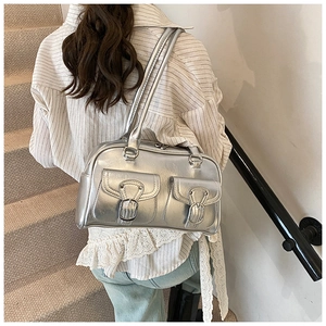 Silver metallic shoulder bag with buckle pockets worn by a model on a staircase