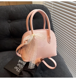 Vue détaillée du sac à main rose grainé avec décoration en nœud de dentelle blanche