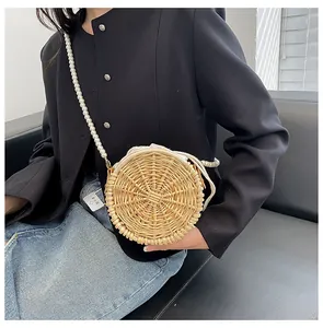 Close-up of circular woven straw bag featuring pearl chain strap and drawstring lining