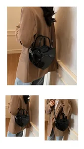 Detail of black heart-shaped shoulder bag featuring a large bow and shiny finish