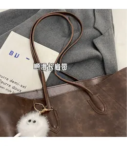 Detail of dark brown tote bag with vintage texture and cute plush monster charm