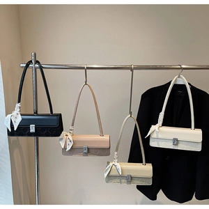 Detail of four stylish rectangular handbags in black, pink, beige, and cream with silk scarves