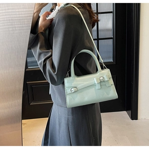 Mint green crossbody bag with bow detail worn over a grey suit for a chic office look