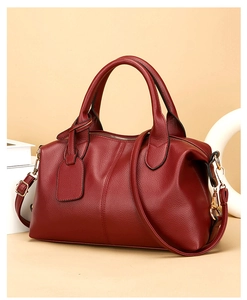 Close-up of red lychee grain leather Boston bag with golden hardware and top handles