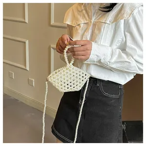 Detail view of a handmade pearl beaded rice ball bag worn by a model in casual wear