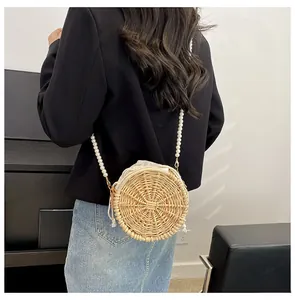 Detail of round straw bag with pearl strap and drawstring lining on a modern outfit