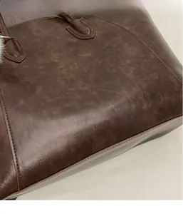 Close-up of vintage brown tote bag showing textured synthetic leather and reinforced stitching