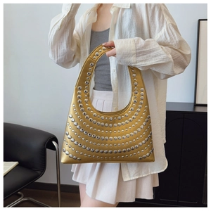 Sac à main demi-lune doré avec rivets argentés porté par un mannequin dans un salon