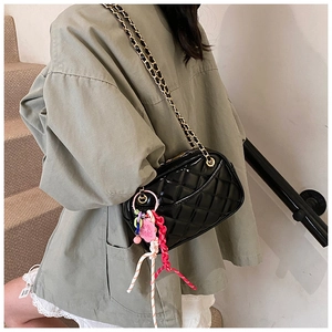 Close-up of black quilted patent leather chain bag with colorful woven charms