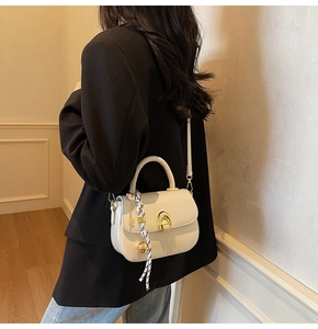 Close-up of cream saddle bag with gold horseshoe buckle and elegant geometric scarf detail