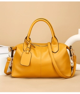 Detail of yellow lychee grain leather boston bag with gold hardware and shoulder strap