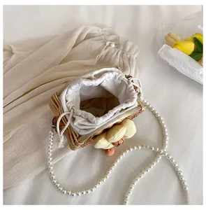 Detail of woven straw mini bag with pearl strap and 3D tulip floral decoration