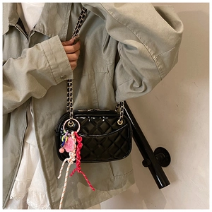 Close-up of black quilted shoulder bag featuring metallic chain and colorful charms